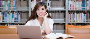 young woman smiling behind laptop