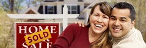 Couple smiling in front of sold sign and house 3