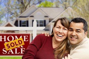 Couple smiling in front of sold sign and house 2