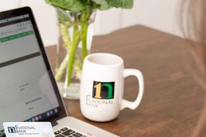 1st national bank mug next to laptop personal computer