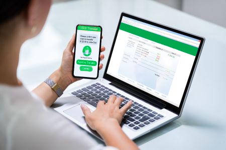 Woman using her phone and computer to access business online banking 1st national bank