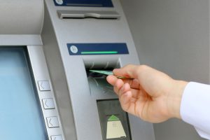 a hand is pressing a button on an atm machine.