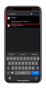 Namedrop the image displays an iphone's search functionality within the Settings menu, with "AirDrop" typed into the search bar. The results show three options: "AirDrop" under the General settings category, "Bringing Devices Together," which appears to be a subcategory under General > AirDrop, and "AirDrop password" under Passwords. The keyboard is visible, suggesting that the user has just finished typing. The user interface is indicative of the iOS style, with a focus on the AirDrop feature, implying that the user is searching for settings related to AirDrop.